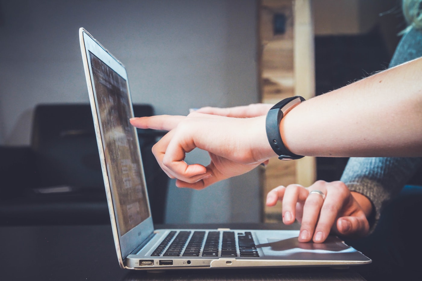 Una persona indica lo schermo di un laptop mentre un'altra digita